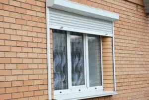 Smart Automations | Brick house window with rolling shutter for home protection.